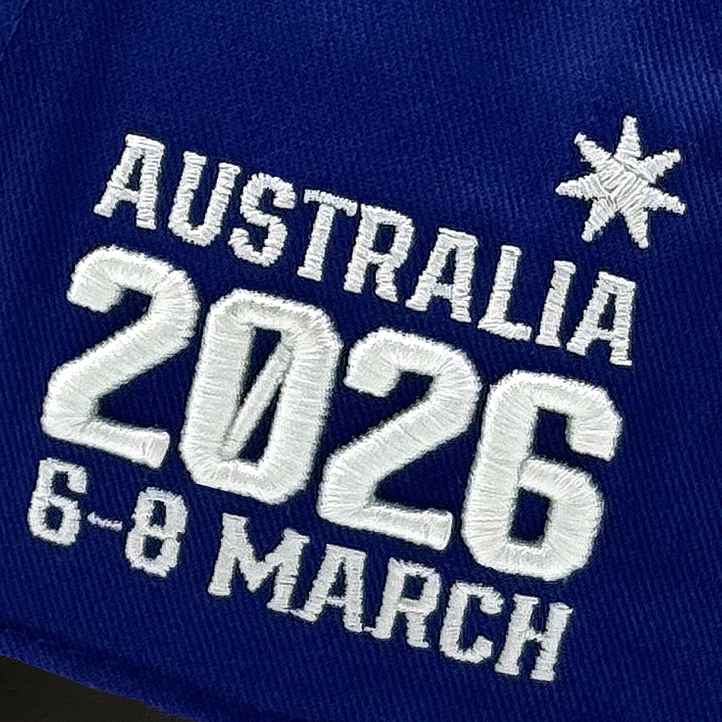 Blue cap with white text 'AUSTRALIA 2026 6-8 MARCH' and star designs.